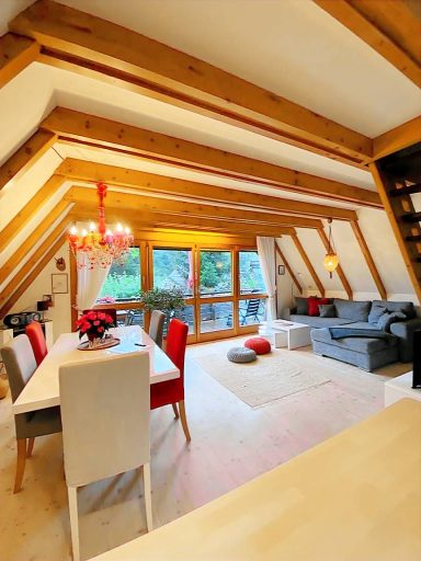 Heller Loft mit Holzdecken, Esstisch, gemütlicher Couch und großen Fenstern.