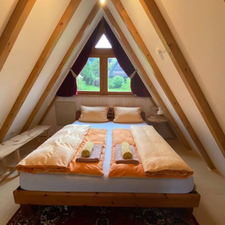 Gemütliches Schlafzimmer im Dachstuhl mit großem Fenster und Aussicht auf den Garten.