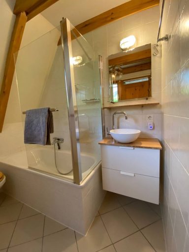 Helles Badezimmer mit Dusche, Waschbecken und Holzregal.
