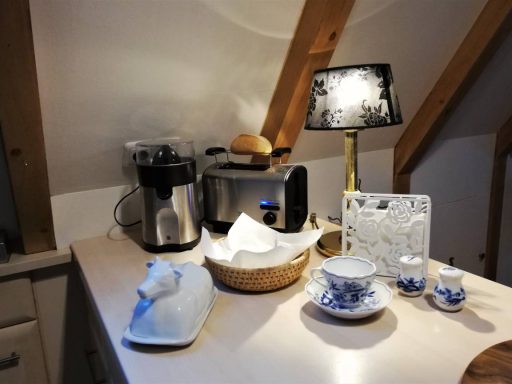 Küchenoberfläche mit einem Toaster, einer Lampe und keramischen Geschirrstücken.