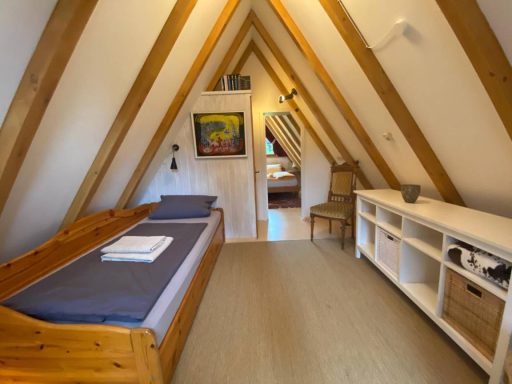 Gemütliches Zimmer im Dachgeschoss mit Holzern, Bett und Schreibtisch.