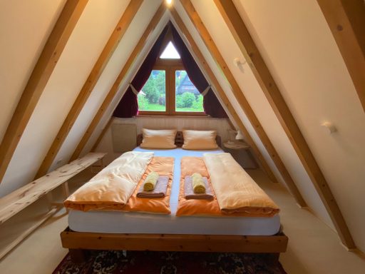 Gemütliches Schlafzimmer im Dachgeschoss mit einem Doppelbett und Fensterblick ins Grüne.