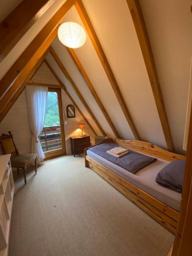 Gemütliches Schlafzimmer im Dachgeschoss mit Holzrahmen, Fenster und Einzelbett.