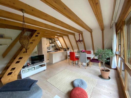 Helles, modernes Wohn- und Esszimmer mit Holzbalken und gemütlichen Möbeln.
